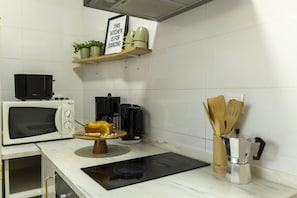 A kitchen with a microwave, coffee maker, and wooden utensils on the counter.