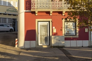 A building with a red facade, a white door, and a balcony with ornate metal railings.