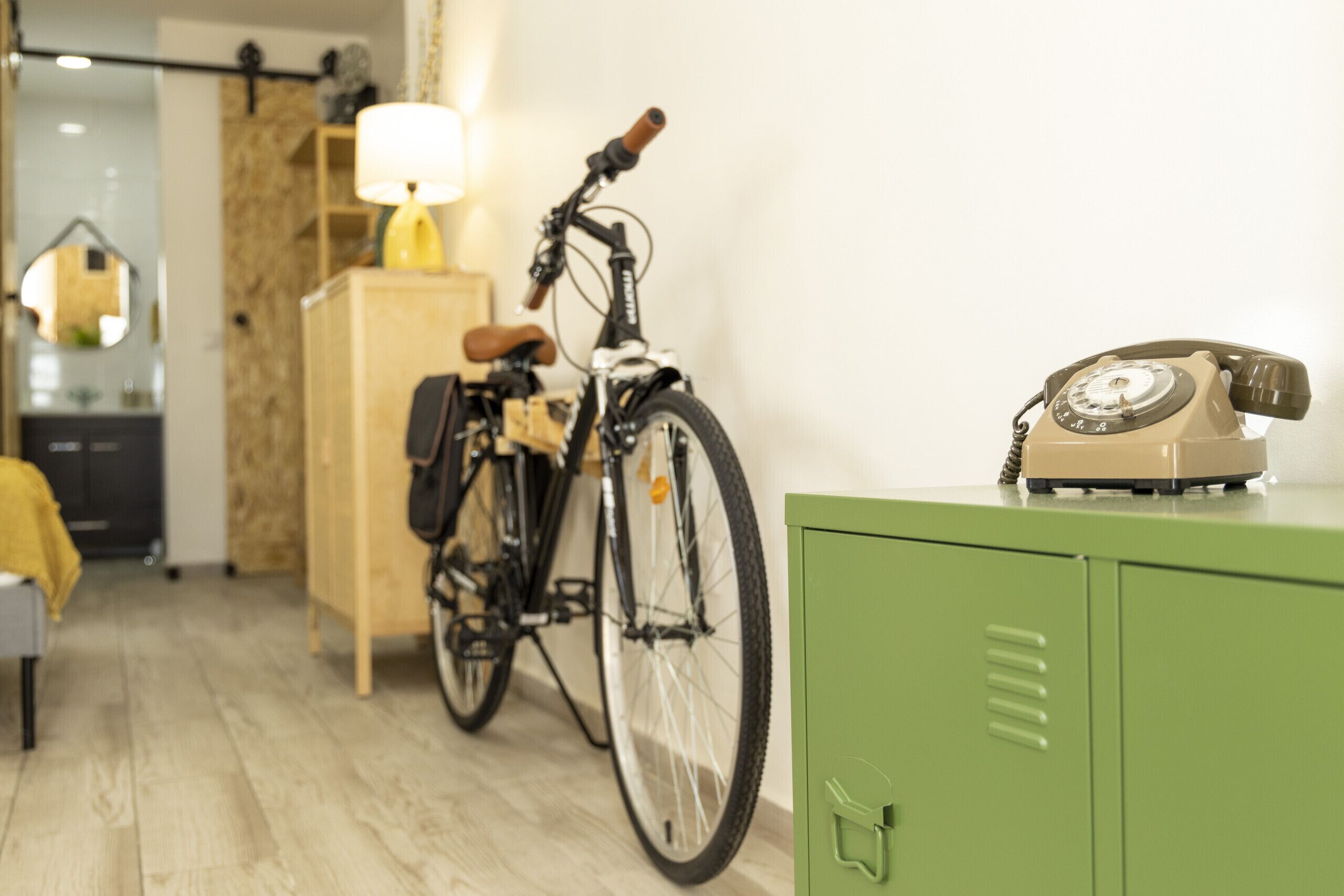 A room with a bicycle, a telephone, and a green cabinet.