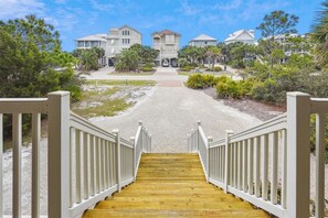 A wooden staircase leading to a gated entrance of a residential area with multiple houses.