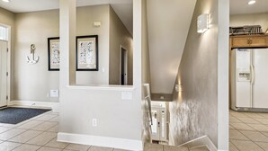 A modern interior with a kitchen area, a framed picture of birds, and a staircase. - Welcome to Waterbird Watch! (St. George Island)