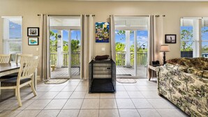 A spacious living room with a dining area, a balcony with a view, and a pet cage. - Welcome to Waterbird Watch! (St. George Island)