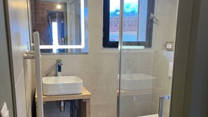 A modern bathroom with a glass-enclosed shower, a sink, and a toilet.