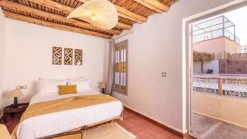 Un dormitorio con cama, techo de madera, ventana y balcón.