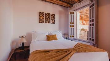 Quarto com cama, mesa de cabeceira, janela com vista e decoração nas paredes.