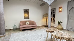 Un patio amplio con un sofá color crema, una mesa redonda de madera y una lámpara decorativa.