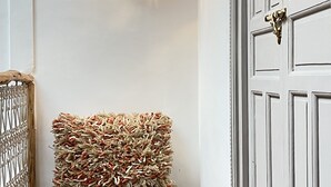 Un pasillo con una puerta blanca, dos lámparas de pared y un reposapiés texturizado.