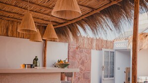 Un espacio abierto con techo de paja, muebles de madera y lámparas de ratán colgantes.
