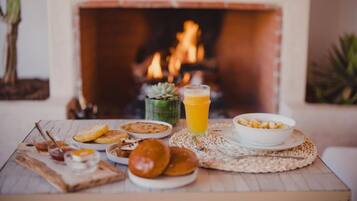 A breakfast setting with a table, a bowl of cereal, a glass of orange juice, and various pastries.