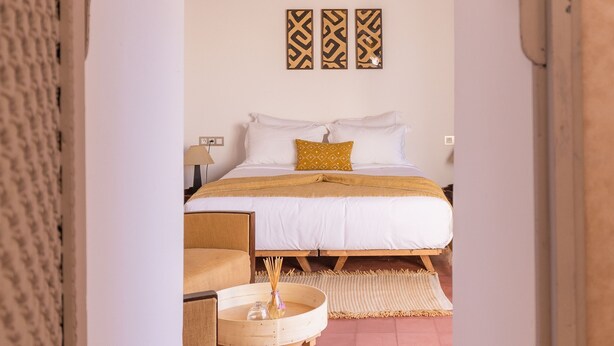 Un dormitorio con una cama, una mesita redonda pequeña y una lámpara colgante.