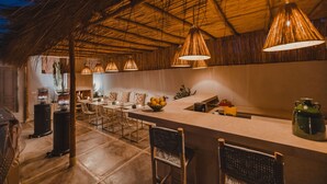 Una cocina moderna con una isla grande, iluminación colgante y un techo rústico.