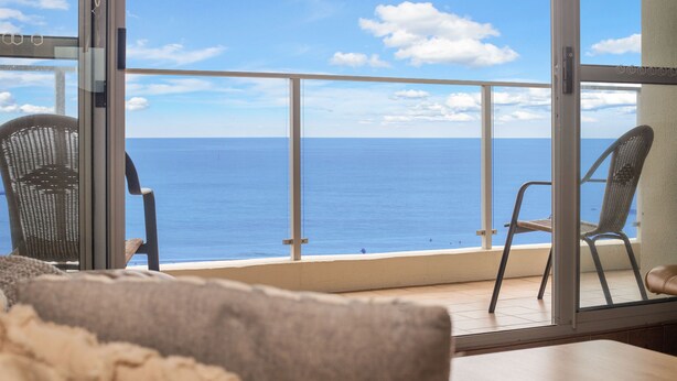 A balcony with two chairs facing the sea, a glass door, and a view of the ocean. - Oceanic 7 - Opposite from main beach (Forster)