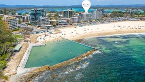 A coastal resort with a swimming pool, beach, and multiple high-rise buildings. - Oceanic 7 - Opposite from main beach (Forster)
