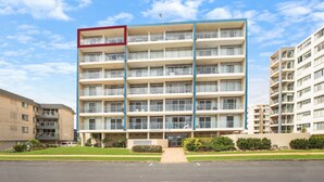 Un hôtel à plusieurs étages doté d’une entrée principale, de balcons à chaque étage et d’un espace de stationnement à l’avant.