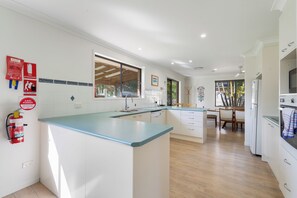 Una cocina moderna con una isla central, un comedor con vistas y un extintor en la pared.