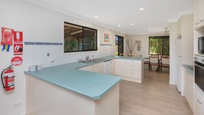 A modern kitchen with a light blue countertop, white cabinets, and a built-in oven. - Spacious. Tropical. Waterfront. (Tuncurry)
