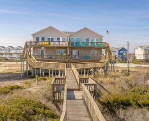A beachfront property with a wooden deck leading to a multi-level building with balconies. - Followin The Son - Amazing 4 BR Oceanfront Duplex; Great Views! (North Topsail Beach)