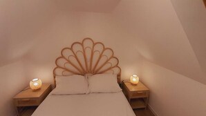 A bedroom with a unique scalloped headboard, two bedside lamps, and a neatly made bed.
