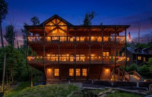 Una cabaña de madera de varios pisos con balcones, una bandera y un porche.