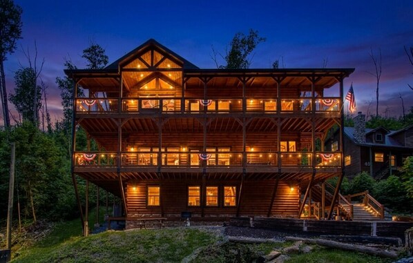 Une cabane en bois à plusieurs étages, dotée de balcons, d’un drapeau et d’un porche.
