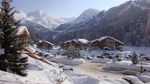 A snow-covered mountain resort with wooden cabins and a ski slope.