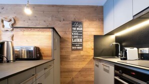 A modern kitchen with wooden wall paneling, stainless steel appliances, and a motivational quote on the wall.