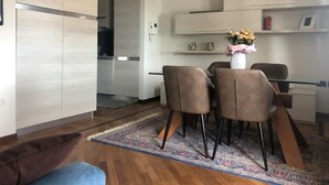 Une cuisine moderne avec des meubles blancs, un coin repas avec quatre chaises et une petite table agrémentée d’un vase de fleurs.