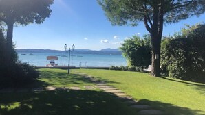 Un sentier qui mène à un lac où l’on peut voir des bateaux, un banc et un lampadaire.