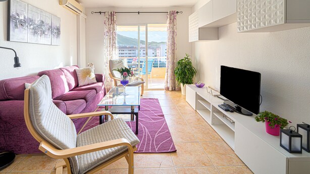 Un soggiorno moderno con divano, poltrona, televisore e vista sul balcone.