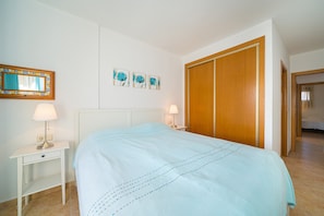 Un dormitorio con cama, mesitas de noche, un espejo y un armario.