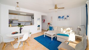 Un salon moderne avec un canapé blanc, une table basse et un coin repas comprenant des chaises et une table.