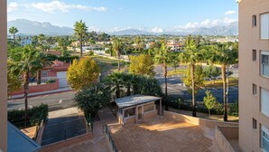 Un quartier résidentiel offrant une vue sur les montagnes, les palmiers et un parking.