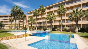 Un hôtel doté d’une piscine, de palmiers et d’un immeuble à plusieurs étages.