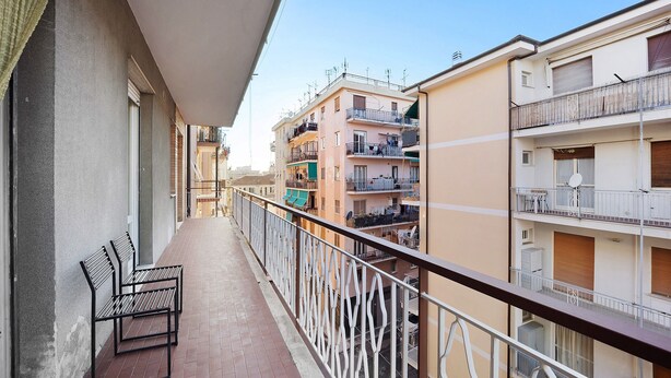A balcony with two metal benches, a railing, and a view of adjacent buildings.