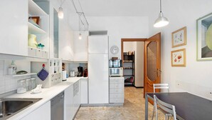 A modern kitchen with white cabinetry, a built-in dishwasher, a microwave, and a dining area with a dark table and metal chairs.