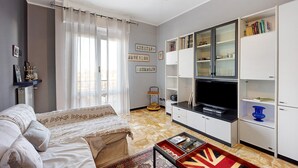 A living room with a sofa, a coffee table, a TV, and a bookshelf.
