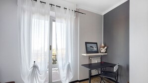 A room with a sliding glass door, a small table with a chair, a radiator, and a shelf with a picture.