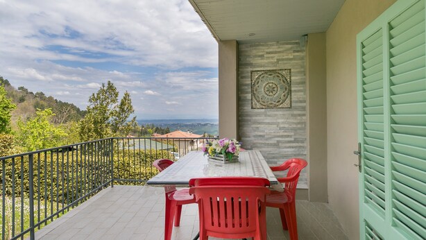 Un balcón con una mesa y sillas, un muro decorativo y vistas del paisaje.