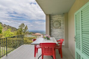 A balcony with a table and chairs, a decorative wall, and a view of the landscape. - Apartment "Appartamento Stella" with Private Balconies, Private Terrace & Wi-Fi (Chianni)