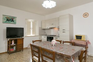 A compact kitchen with a dining area, a television, and a microwave.