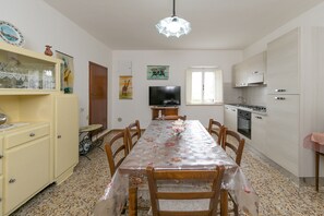 A compact kitchen with a dining table, chairs, a television, and a cabinet.