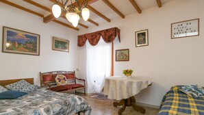 Un dormitorio con cama, una silla, una mesa y una ventana con cortinas.