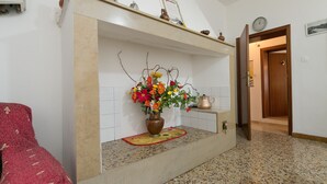 Un área de recepción con suelo de baldosas, mostrador de recepción, un jarrón con flores, un reloj y una puerta que da a otra habitación.