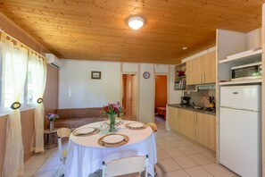 Un coin repas avec une table dressée pour quatre personnes, une cuisine équipée d’appareils modernes et un plafond en bois.