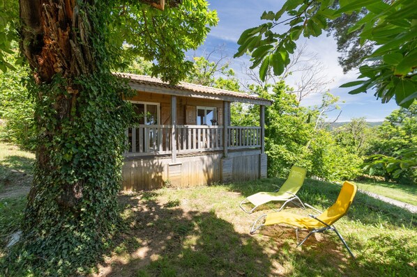 Une maison en bois dotée d’un balcon, entourée de verdure.