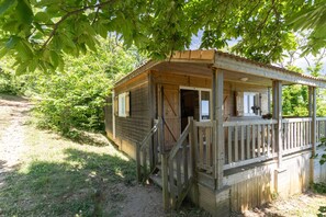Une cabane en bois avec une véranda, une porte et une fenêtre.