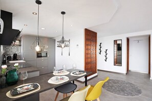 A modern kitchen with a dining area, a staircase, and a wooden door.