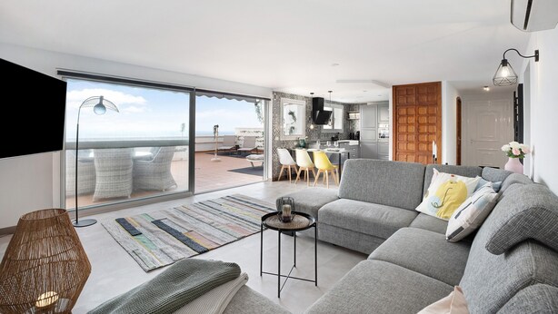 A modern living room with a grey sofa, a small table, and a large window. - Apartment "Casa Hola Mar" Directly on the Coast with Infinity Sea View (Los Realejos)
