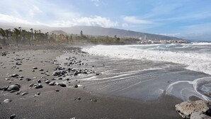 A beach with a rocky shoreline, waves, and a distant mountain. - Apartment "Casa Hola Mar" Directly on the Coast with Infinity Sea View (Los Realejos)