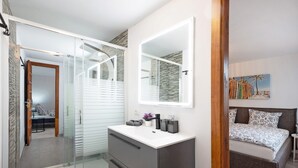 A bedroom with a bed, bedside table, and a large mirror. - Apartment "Casa Hola Mar" Directly on the Coast with Infinity Sea View (Los Realejos)
